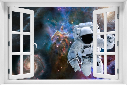 Fototapeta Naklejka Na Ścianę Okno 3D - Astronaut near Mystic Mountain of Carina Nebula near far galaxies and stars. Science fiction. Elements of this image were furnished by NASA.