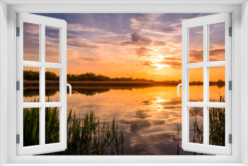 Fototapeta Naklejka Na Ścianę Okno 3D - Scenic view of beautiful sunset or sunrise above the pond or lake at spring or early summer evening with cloudy sky background and reed grass at foreground. Landscape. Water reflection.