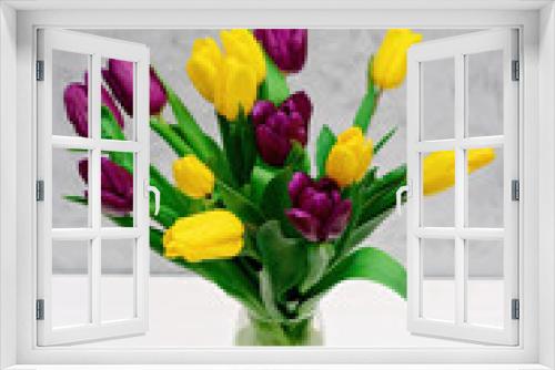 Fototapeta Naklejka Na Ścianę Okno 3D - Bouquet of purple and yellow spring tulip flowers in a glass vase on a light background. Mothers Day. International Women's Day.