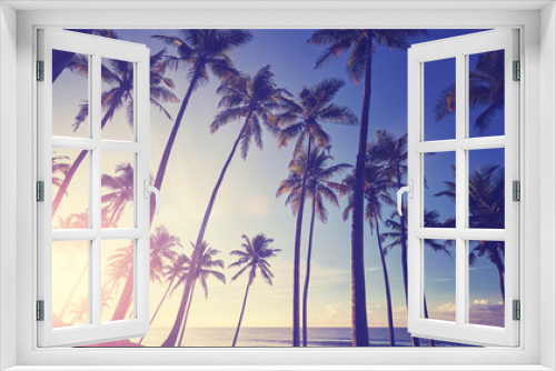 Fototapeta Naklejka Na Ścianę Okno 3D - Tropical beach with coconut palm trees silhouettes at sunset, color toning applied.