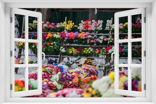 Fototapeta Naklejka Na Ścianę Okno 3D - a point of sale with many artificial flowers, bouquets and wreaths near the cemetery sells jewelry and traditional offerings to the graves of the dead in memory of living relatives
