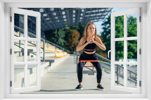 Young sporty woman doing exercises with rubber band outdoor