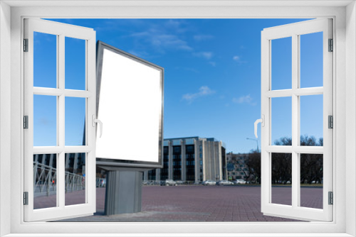Fototapeta Naklejka Na Ścianę Okno 3D - Vertical billboard Advertising canvas mockup on a city square on a sunny good day. With white space for mock-up posters