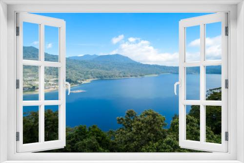 Fototapeta Naklejka Na Ścianę Okno 3D - A panoramic view on The Twin Lake, Bali, Indonesia. The lake is surrounded by lush green plants. There are small hills all around the lake. Touristic attraction. Biggest lake on Bali