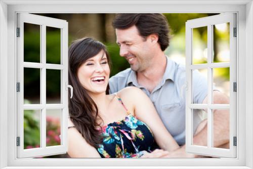 Happy Young Man and Woman Laughing While Sitting on Sidewalk