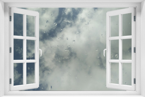 Fototapeta Naklejka Na Ścianę Okno 3D - blauer himmel mit wolken durch eine glasscheibe mit regentropfen
