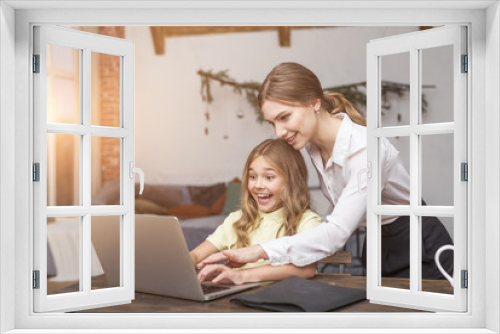 Young emotional girl very excited and working with laptop, her mother helps doing it