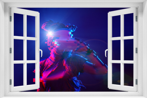 Fototapeta Naklejka Na Ścianę Okno 3D - Woman is using virtual reality headset. Neon light studio portrait. Image with glitch effect.
