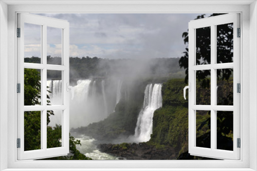 Fototapeta Naklejka Na Ścianę Okno 3D - Iguazu roaring waterfalls against a jungle and gray sky