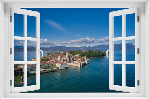 Fototapeta Naklejka Na Ścianę Okno 3D - Sirmione town, Lake Garda, Italy. Aerial view of Sirmione. The historical part of the city.  In the background mountains in the snow and blue sky.  Side view of the island.