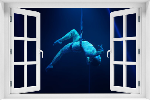 Fototapeta Naklejka Na Ścianę Okno 3D - Flexible young woman make aerial performance , blue light, flexible split aerial circus show. Stretching women. Gymnast upside down