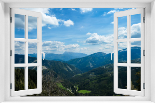 Fototapeta Naklejka Na Ścianę Okno 3D - A vast view on Alpine valley from the upper parts of Himmeleck in Austria. The valley is lush green. There are many mountain ranges in the back. Spring coming to the Alps. Dense forest