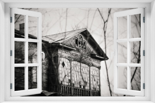 Fototapeta Naklejka Na Ścianę Okno 3D - An old abandoned damned wooden house with broken Windows stands in the middle of a grove of trees. Black and white filter.