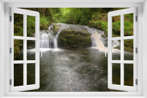 Fototapeta Naklejka Na Ścianę Okno 3D - Stunning waterfall flowing over rocks through lush green forest