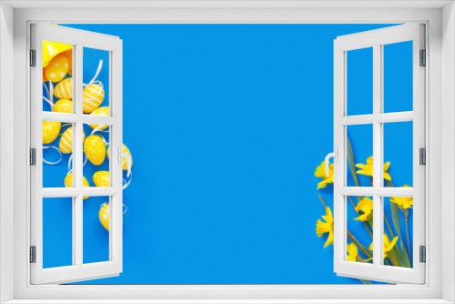 Bouquet of beautiful yellow daffodils with  eggs on blue paper background to easter.