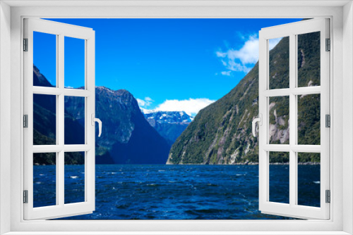 Fototapeta Naklejka Na Ścianę Okno 3D - Beautiful shot of Milford Sound with snow capped mountains in the background taken on a sunny spring day, New Zealand