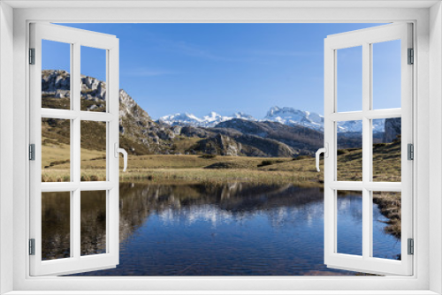 mountainous landscape, small lake in which the mountain, the meadow and the blue sky are reflected