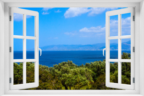 Cyprus mediterranean seascape. View to the bay with green grove in front and hills with blue clouded sky as a background. View from the hill