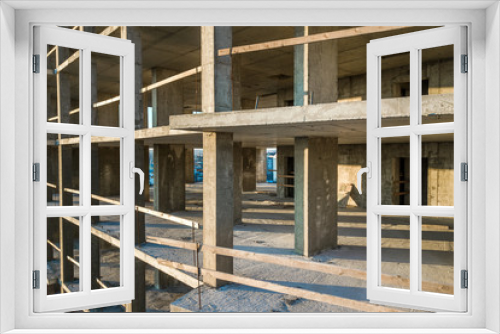 Fototapeta Naklejka Na Ścianę Okno 3D - Interior of a concrete residential apartment building room with unfinished bare walls and support pillars for future walls under construction.