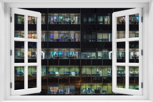 Modern office building with big windows at night timelapse, in windows light shines