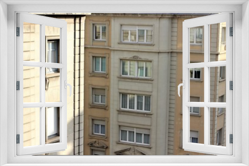 Fototapeta Naklejka Na Ścianę Okno 3D - sunny windows on the upper floors of two beige buildings, one in the foreground, the second in the background.