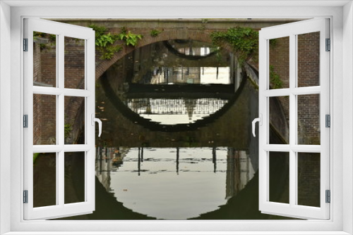 Fototapeta Naklejka Na Ścianę Okno 3D - Eine halbrunde Brücke spiegelt sich in Wasser und ergibt ein ganzer Kreis. Das Geländer der Brücke und andere Brücken reflektieren sich verzerrt und ergeben eine schöne Füllung des Kreises.