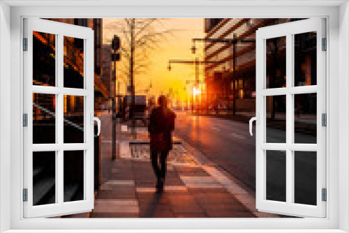 Silhouette backview of a girl walking in the empty streets at low evening sunset light. Historic and famous harbour district Speicherstadt and modern Hafencity  in Hamburg, Europe