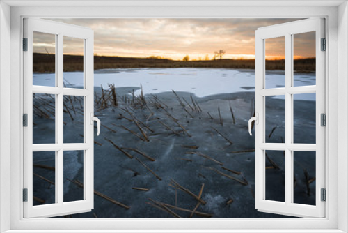 Fototapeta Naklejka Na Ścianę Okno 3D - Sunset sky over the shoreline of a frozen wetland habitat.