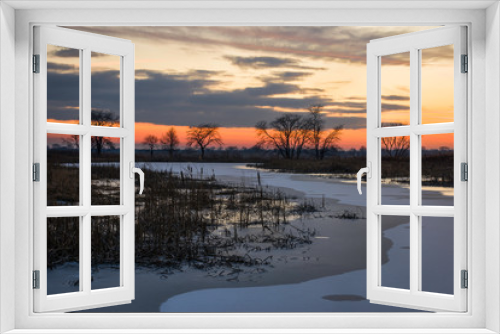 Fototapeta Naklejka Na Ścianę Okno 3D - Vivid winter sunset colors over a frozen wetland conservation area.