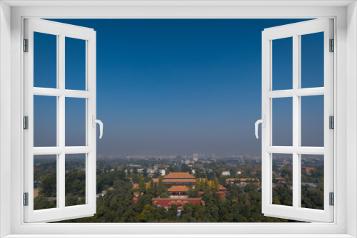 Scenic view overlooking the city of Beijing from Jingshan Park Palace gardens with temples, houses, rooftops and hazey blue sky in the background.