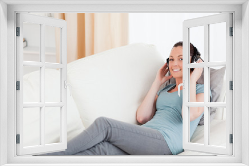 Good looking female using headphones while lying on a sofa