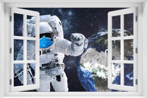 Fototapeta Naklejka Na Ścianę Okno 3D - Astronaut in blue medical mask near Earth planet of solar system at night. It is important to wear mask. Science fiction. Elements of the image were furnished by NASA