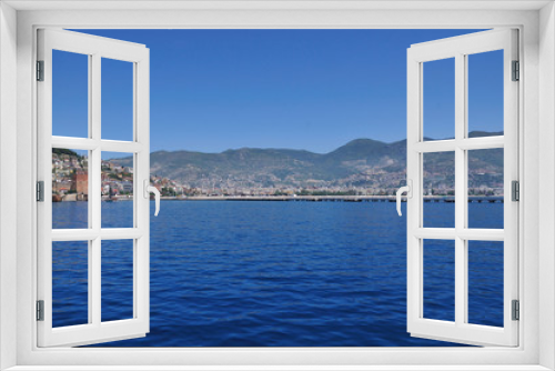 Fototapeta Naklejka Na Ścianę Okno 3D - A magnificent view of the calm blue sea, the city on the mountain and the sky. Beautiful summer day on the sea shore.