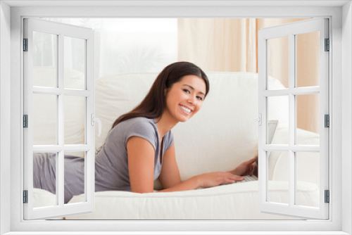 cute woman lying on sofa with notebook