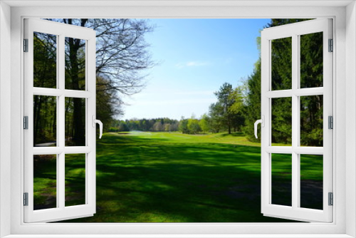 Fototapeta Naklejka Na Ścianę Okno 3D - Blick auf einen leeren Golfplatz / Golfbahn mit Rasensprenger im Frühling 