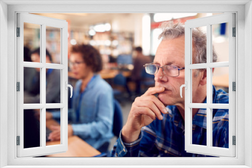 Group Of Mature Adult Students In Class Working At Computers In College Library