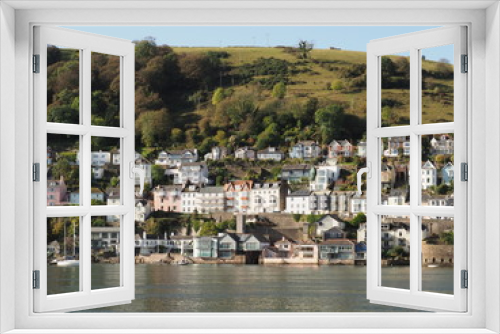  a hill in Kingswear , Devon seen across the River Dart in sunshine showing neat and colourful houses