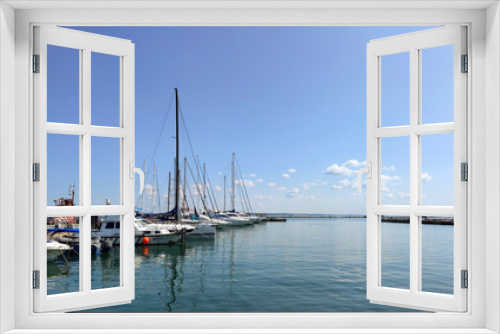 Wooden pier with many yachts stand and prepare for regatta, calm sea and small clouds in the sky