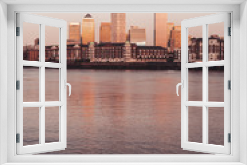 Fototapeta Naklejka Na Ścianę Okno 3D - Canary wharf banking center by the majestic river at sunset with old buildings London Vertical