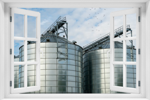 Fototapeta Naklejka Na Ścianę Okno 3D - silver silos on agro manufacturing plant for processing drying cleaning and storage of agricultural products, flour, cereals and grain. Large iron barrels of grain. Granary elevator