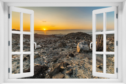 Fototapeta Naklejka Na Ścianę Okno 3D - Amazing sunset over the sea view at Atacama Desert coast. Orange landscape illuminated by the sunlight with an arid scenery full of cactus plants, sand and rocks, a tranquil scene for a lonely place
