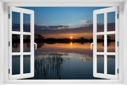 Fototapeta Naklejka Na Ścianę Okno 3D - Sunset over a calm lake with reeds, the evening cloud reflecting in the water