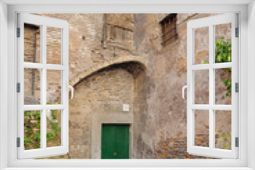 Fototapeta Naklejka Na Ścianę Okno 3D - old house with a closed green door. The corner of the building is an unusual shape. Nobody seems to live there. .Empty courtyard