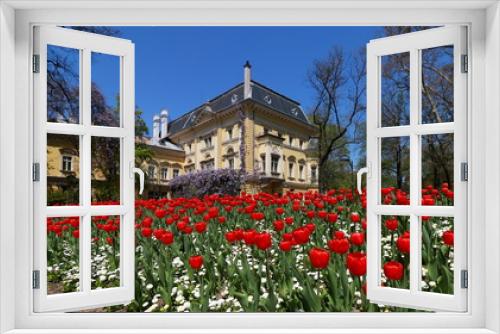 Fototapeta Naklejka Na Ścianę Okno 3D - Landscape with yellow baroque house surrounded by green trees and a field of pink red flowers in the middle of Sofia, Bulgaria
