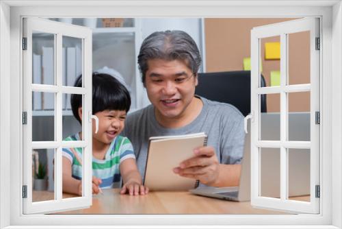 Asian father working at the home office with a laptop and teaching homework with a daughter. New lifestyle normal during a quarantine. Concept of stay home, freelance and fatherhood concept