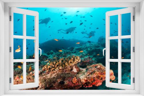 Fototapeta Naklejka Na Ścianę Okno 3D - Colorful underwater scene of fish and coral with scuba divers swimming in the background