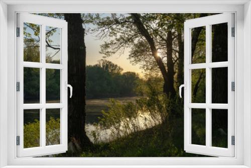 Fototapeta Naklejka Na Ścianę Okno 3D - Early spring. Morning dawn over the lake in a misty, thoughtful haze. Beautiful view of the forest covered with fog early in the morning. The sun's rays of light. May.