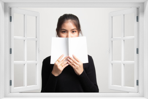 Young Asian woman with a book cover her face.