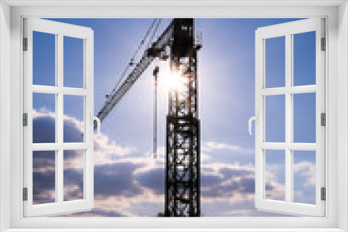 Fototapeta Naklejka Na Ścianę Okno 3D - Silhouette of a crane in a counter-diving. Sunshine and blue sky in the background. Site lift structure.