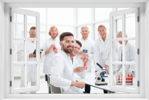 smiling scientist sitting at a laboratory table .